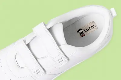 White shoes on a light green background. Inside is a name label, reading "Lucas"