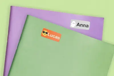Close-up of two notebooks, one purple and one green, both labeled "Anna" and "Lucas".
