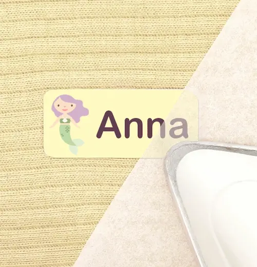 An iron is pressing a name label onto fabric.