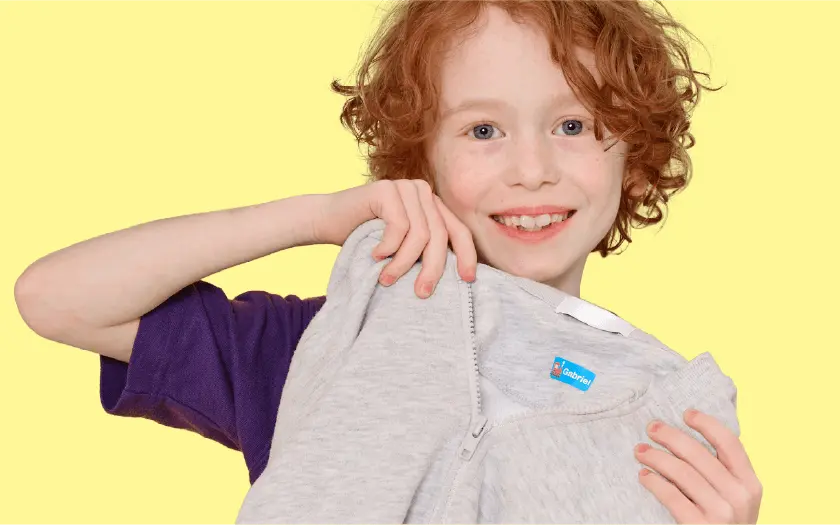 Boy holding up a jumper with an iron-on name label