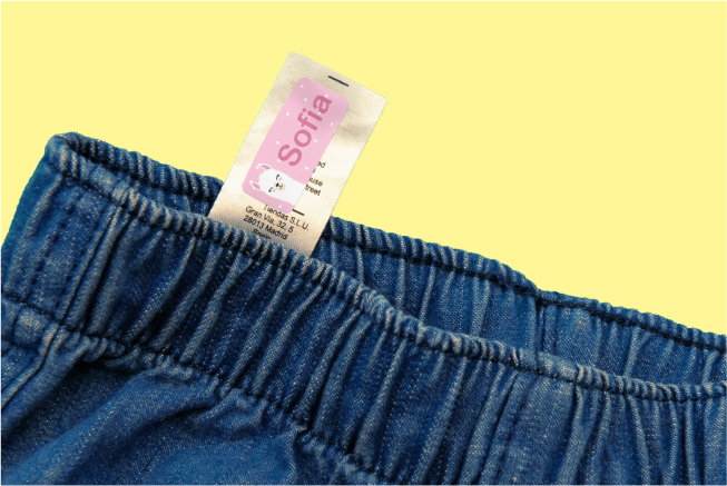 Name sticker applied to the care label of a pair of jeans